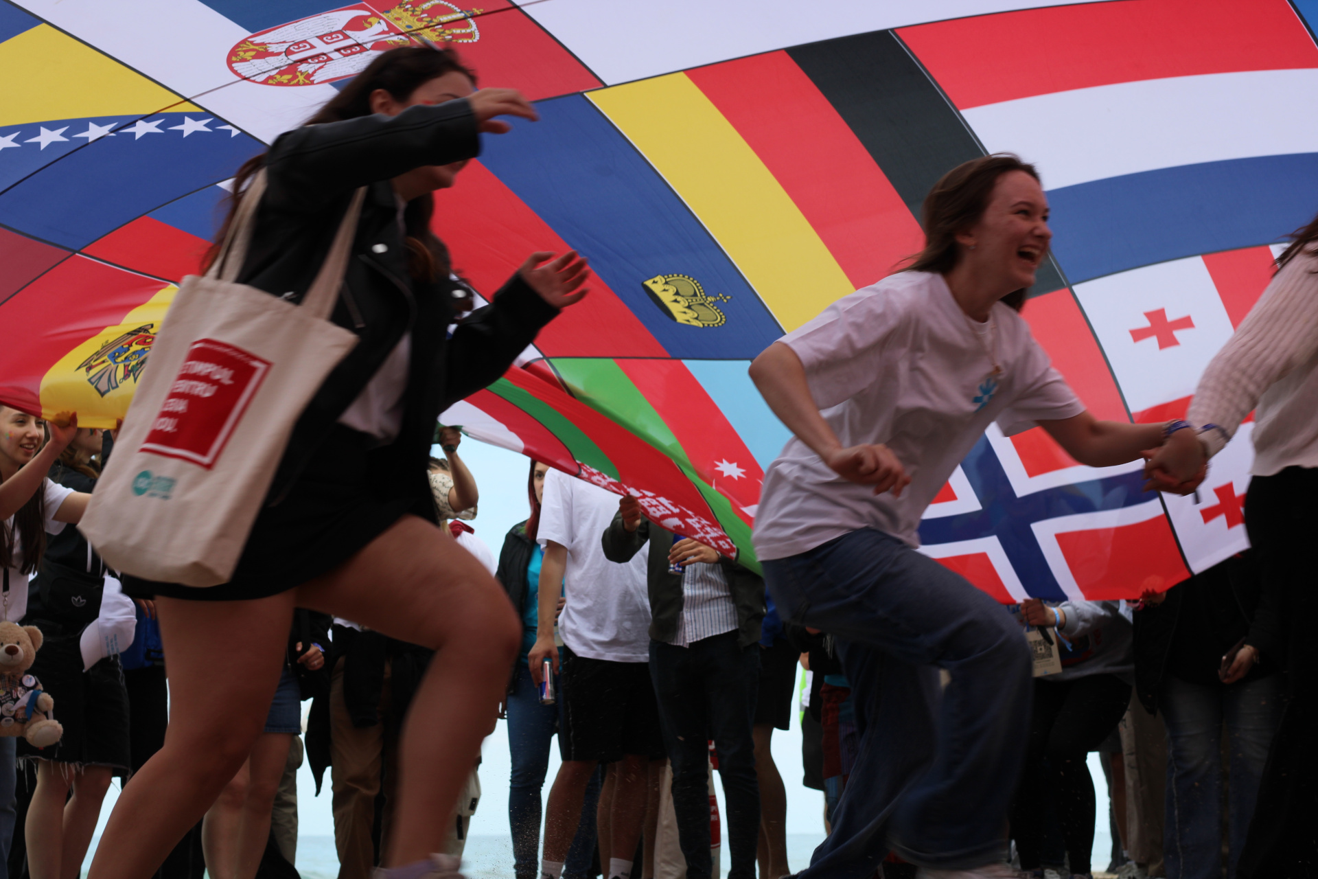 People running under a large flag